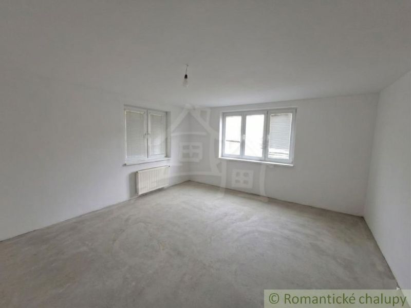 An empty room with windows and a radiator in a family house, floor with decor.