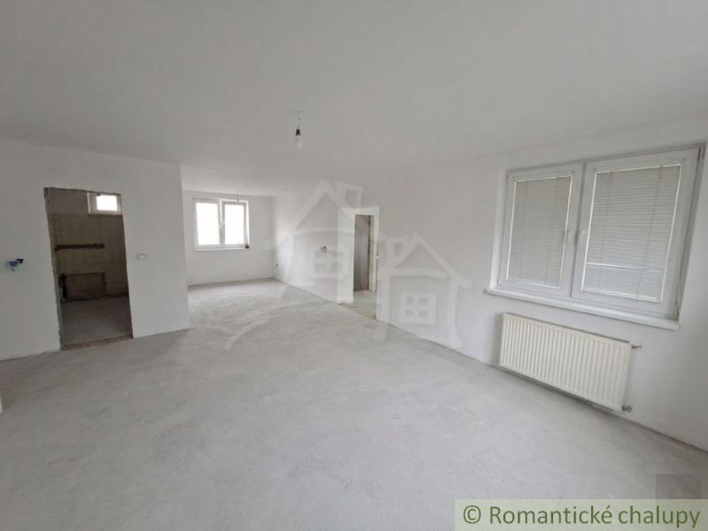 Spacious room in a family house with white walls and large windows.