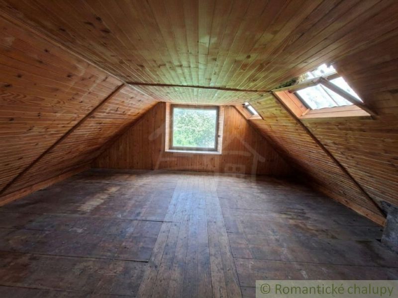 An attic with wooden paneling and a large window in a family house.