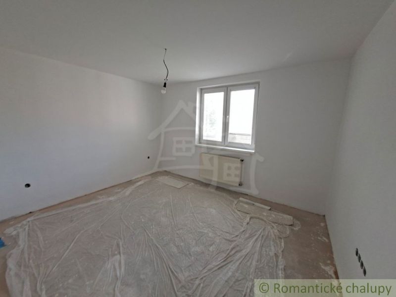 An empty room in a family house, white walls, plastic covering on the floor.