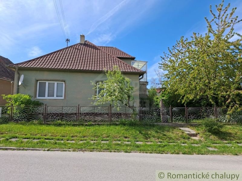 A family house in Orešany with a garden and a decorative fence on a sunny street.