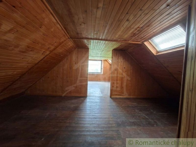 An attic with wooden paneling and windows in a family house.