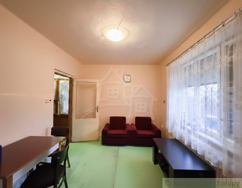 Living room with red seating, table, and curtains, Family house.