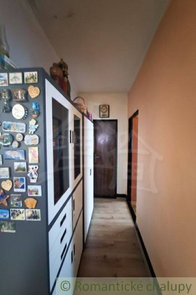 A hallway in a family house with a shelf and a wooden decor floor.