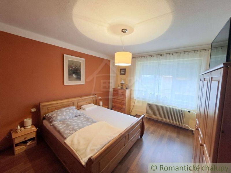 A bedroom in a family house with wooden decor, a bed, and furniture in warm colors.