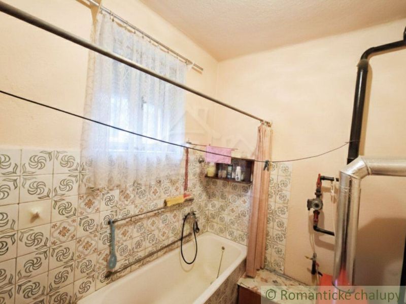 Bathroom with a bathtub in a family house, tiles with a floral pattern and a curtain.