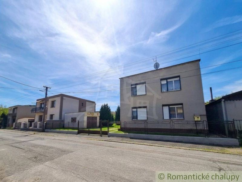 Family houses in Mýtna near a street with a clear sky and a fence.