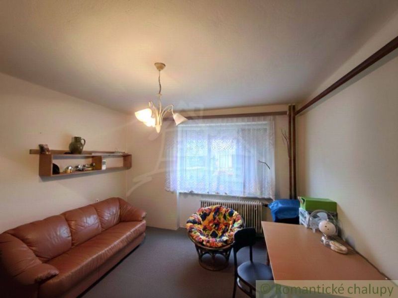 A room in a family house with a brown sofa, a desk, and a colorful armchair.