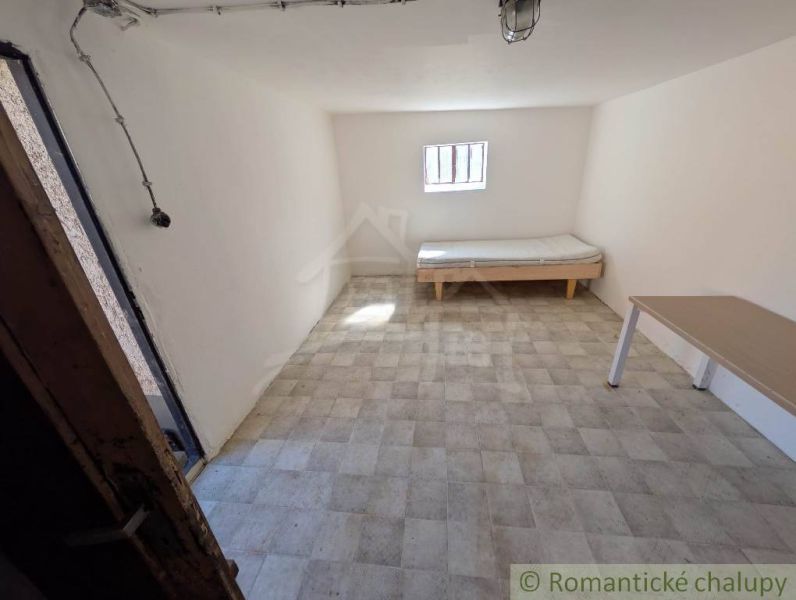 A room in a family house with a bed, a table, and a window, light-colored walls.