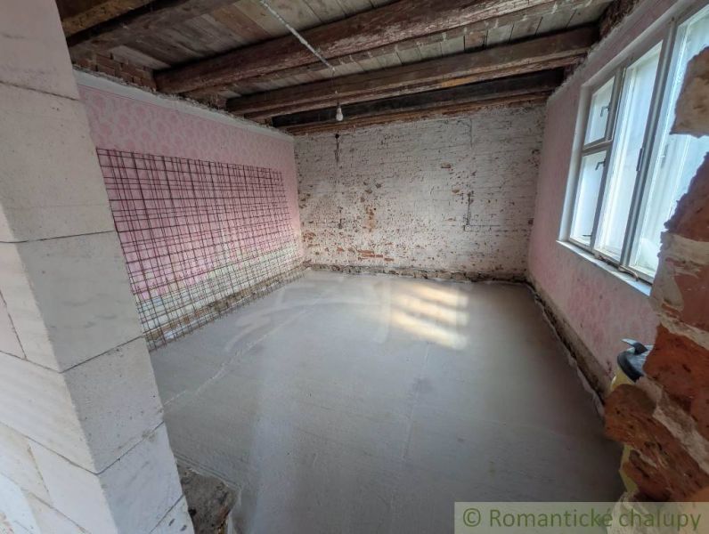 Interior with exposed brick walls and wooden ceiling beams in a family house.