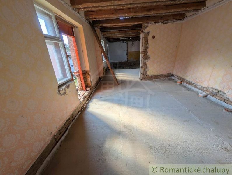 The interior of a family house with exposed wooden ceilings and damaged walls.