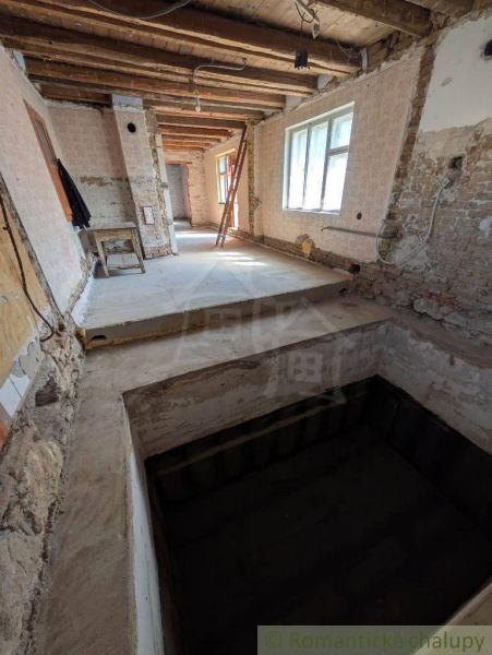 Interior of a family house with an exposed ceiling and raw walls under renovation.