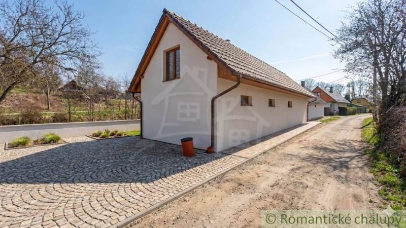 A family house in Sobotište with a paved driveway, surrounded by greenery and trees.