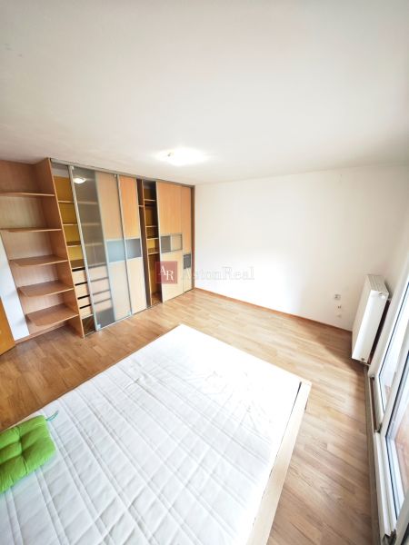 Bright bedroom in a 3-room apartment with wood-patterned flooring and a built-in wardrobe.