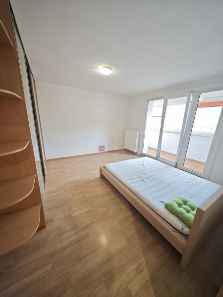 Bright bedroom in a 3-room apartment with a bed and wood-decor flooring.