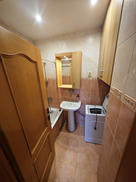 A bathroom in a 3-room apartment with a bathtub, sink, and washing machine.
