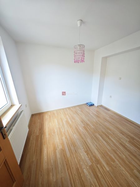 A room in a 3-room apartment with a wall and floor featuring a wooden decor.