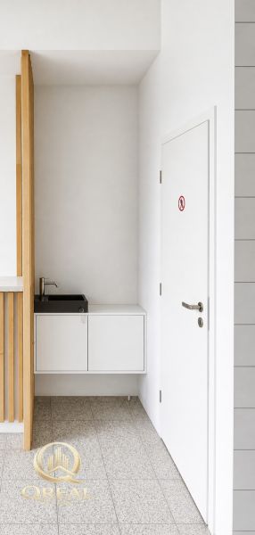 White interior of commercial space with a sink and doors.