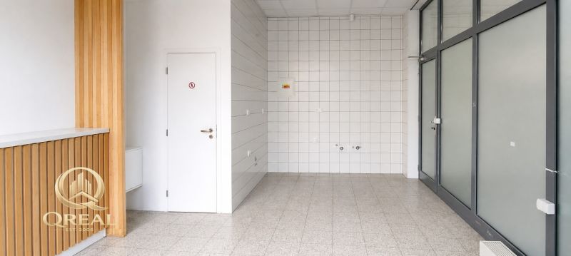 Commercial space with light flooring, white tiles, and wooden decor on the wall.