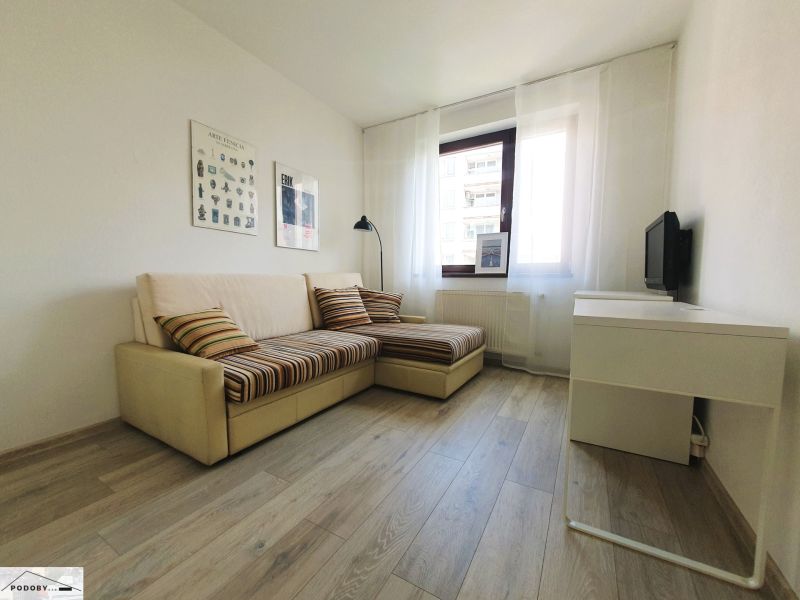 Living room in a three-room apartment with a sofa and a wooden decor floor.