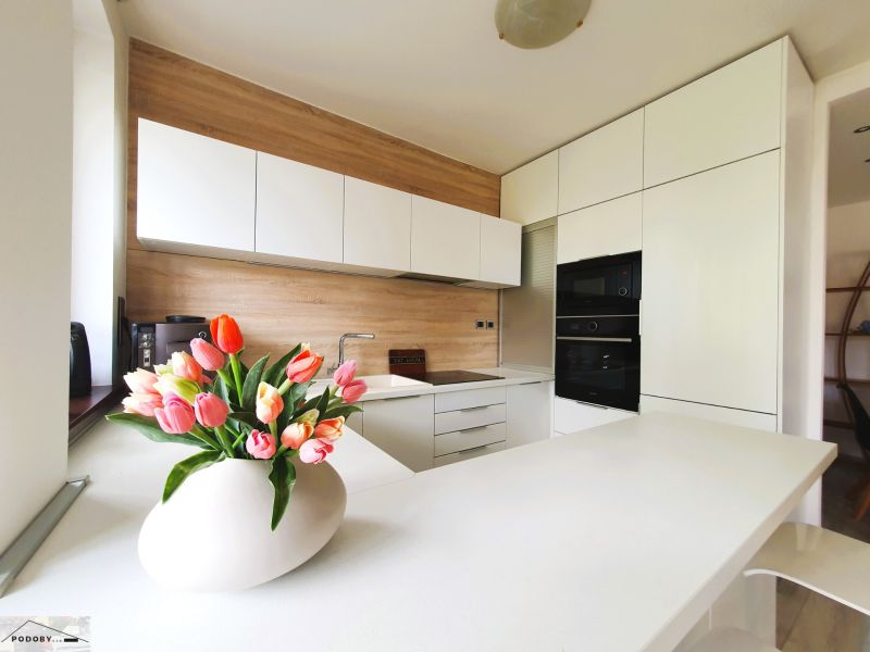 White kitchen with wood decor and tulips in a 3-room apartment.