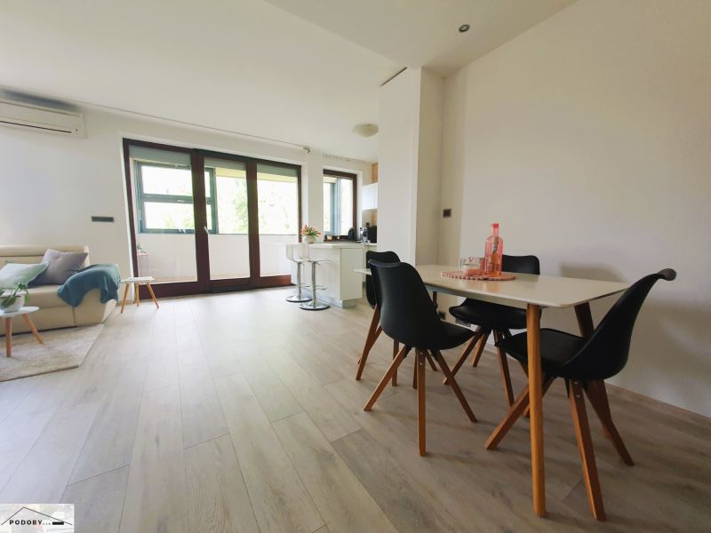 A bright interior of a 3-room apartment with white walls and a floor with a wood decor.