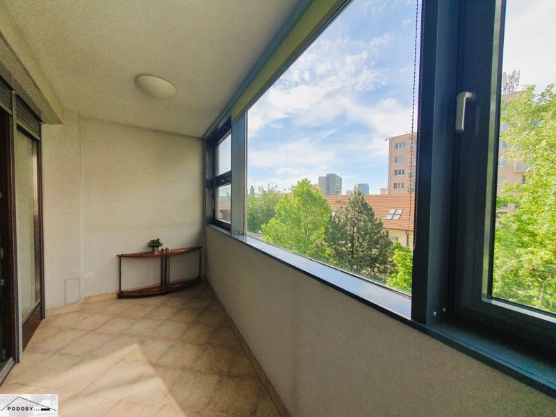 A glazed loggia in a 3-room apartment with a view of greenery and the city panorama.