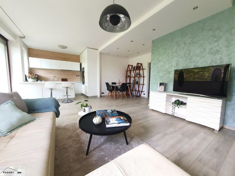 Living room with wood-patterned flooring, open space, and kitchen in a 3-room apartment.