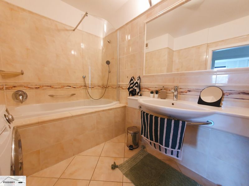 A bathroom with a bathtub, sink, and tiles in a 3-room apartment.