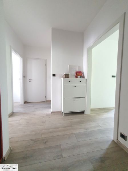 A hallway with white furniture and a wooden decor floor in a 3-room apartment.