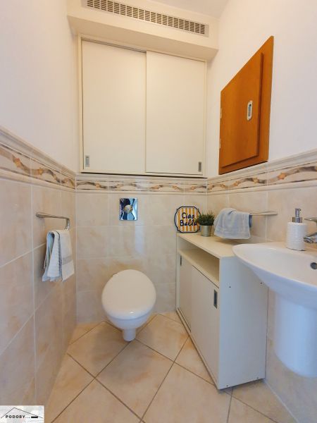 Bathroom in a 3-room apartment with a toilet, sink, and cabinet.