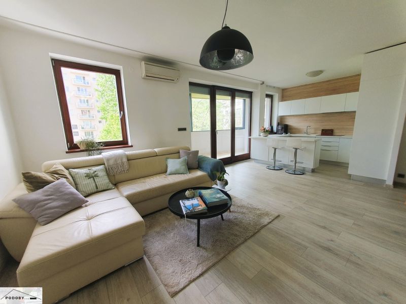 Living room with a kitchenette, sofa, and wooden decor flooring in a 3-room apartment.