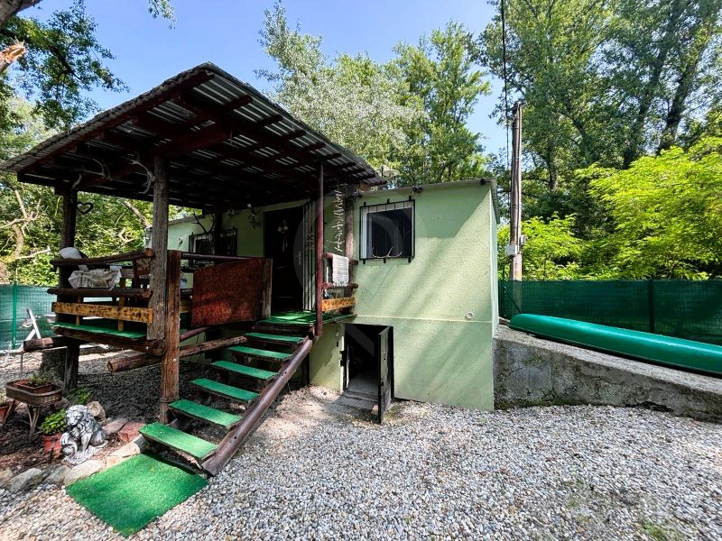 A wooden terrace of the cottage in Gabčíkovo surrounded by greenery and a gravel area.