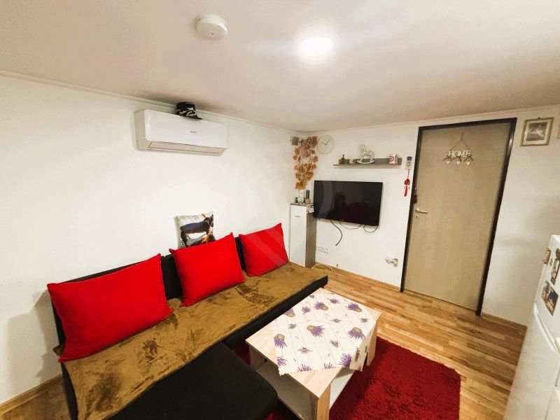A living room in a cottage with a wood-patterned floor and red accessories.
