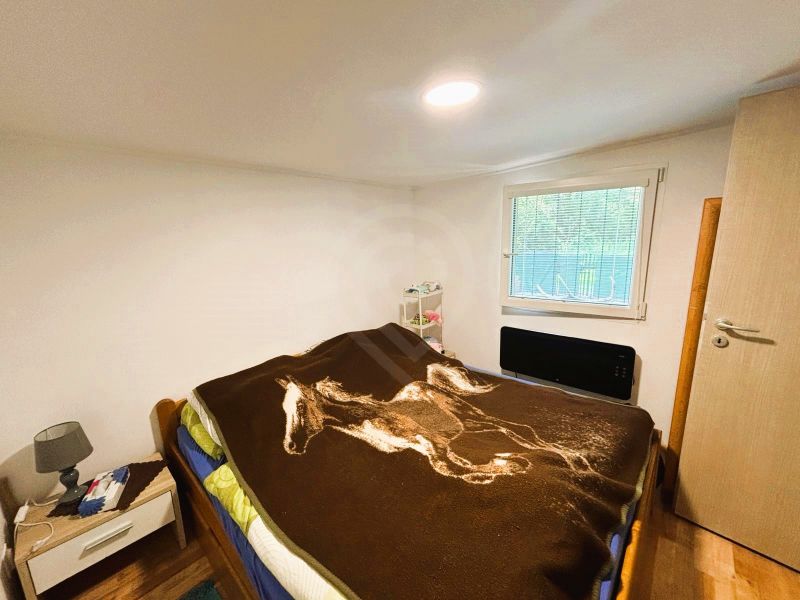 A cottage with a wooden decor floor, a bed, and a nightstand, simple bedroom design.