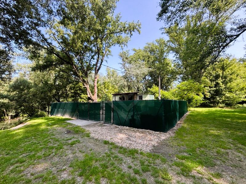 A cottage in Gabčíkovo surrounded by greenery by the river with a fenced plot.