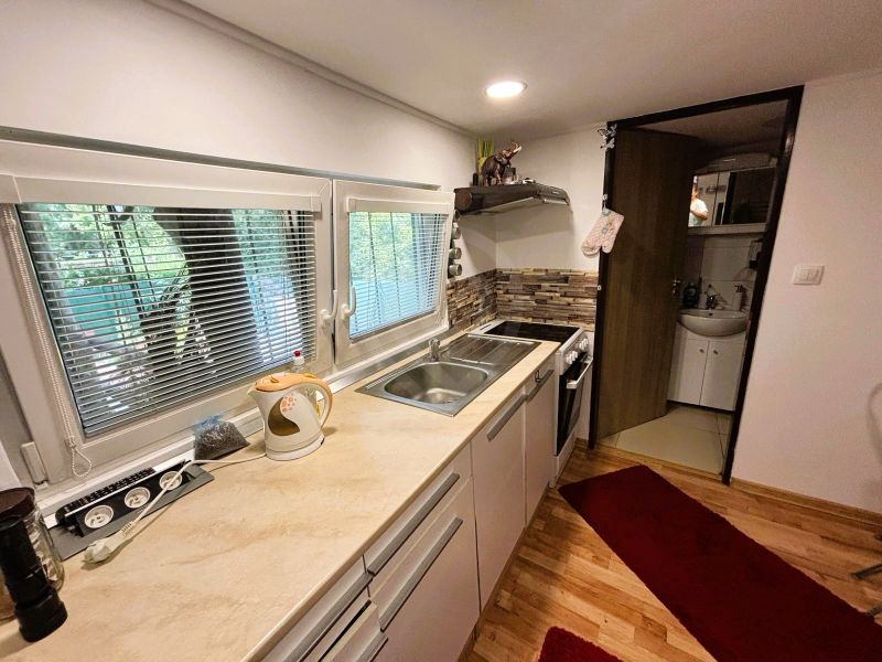 A kitchen in a cottage with a wood-patterned floor, a stove, and wooden decor.