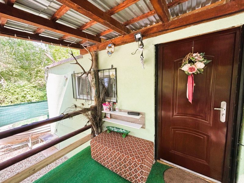 A cottage in Gabčíkovo with a decorative entrance, railing, and seating area near a green space.