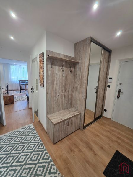 The hallway of a 3-room apartment with a wood-patterned floor and a wardrobe.