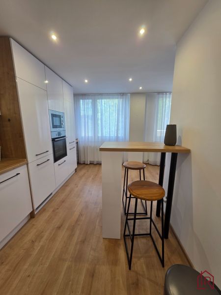 A kitchen with white cabinets, a wooden decor floor, high chairs in a 3-room apartment.