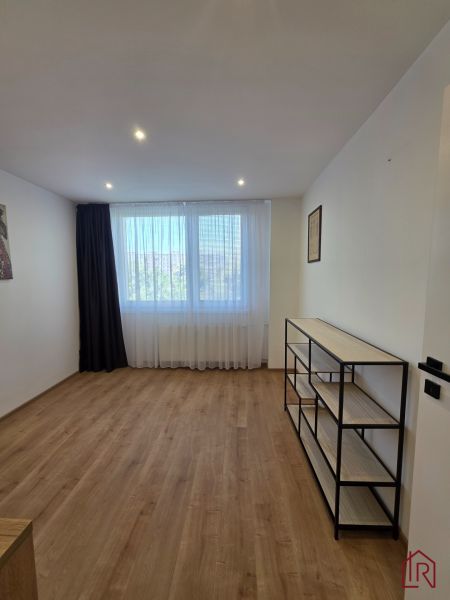 A room with a wooden decor floor and a shelf in a 3-room apartment.
