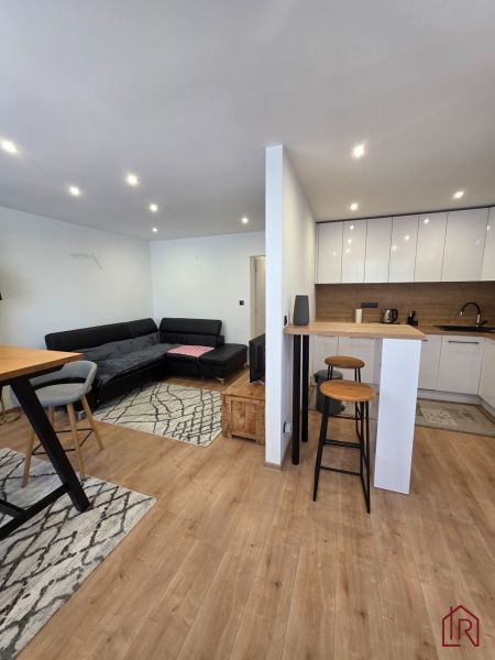 Living room with kitchen in a 3-room apartment, wooden decor flooring, sofa set.