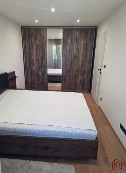 Bedroom with a large wardrobe, bed, and wooden decor flooring in a 3-room apartment.