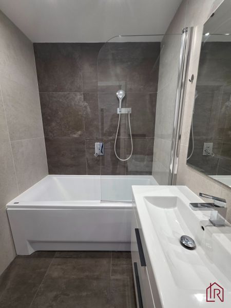 A bathroom in a 3-room apartment with a bathtub, a shower screen, and a modern sink.