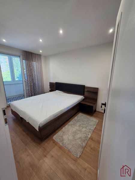 A bedroom with a bed and a wooden decor floor in a 3-room apartment.