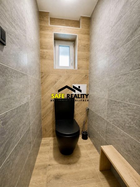 A toilet in a family house with a black toilet and a floor with a wooden decor.
