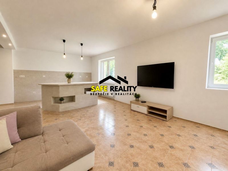 Living room in a family house with a TV, sofa, and tiles.