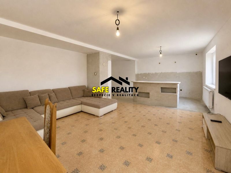 Living room in a family house with a large sofa, TV, and dining table.