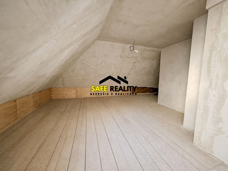 Attic space in a family house with a floor featuring a wooden decor and an unfinished ceiling.