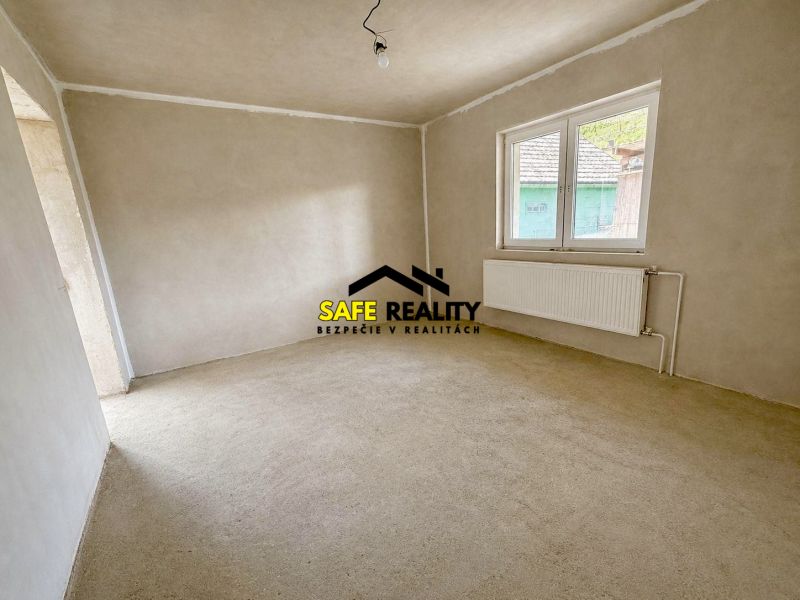 An empty room with a window and a white radiator in a family house.